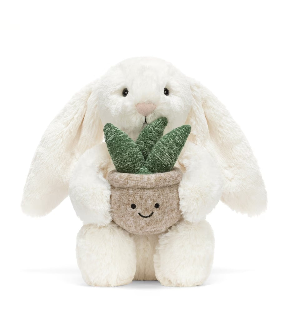 White jellycat bunny holding a plant with a smiley face on the pot. On a white background.